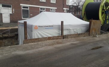 The grey 6x3 m working tent from Visser & Smit Hanab stands in the excavation pit during road works.