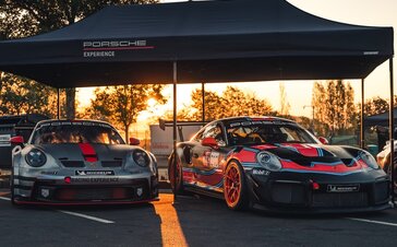 2 Porsche Experience Racing Modelle nebeneinander unter einem schwarzen 6x3 Oxford Faltpavillon mit gerader Blende und schwarzem Alugestell im Hintergrund Sonnenuntergang
