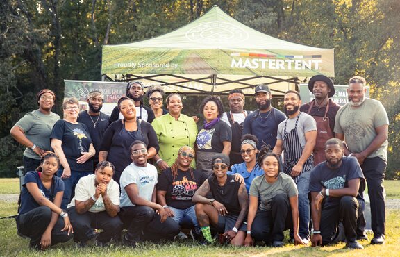 A group of people posed in front of a sponsored non-profit Mastertent.