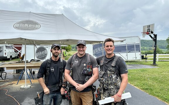 Renovation team standing in front of heavy duty Mastertent brand work tent outside at a job site. 