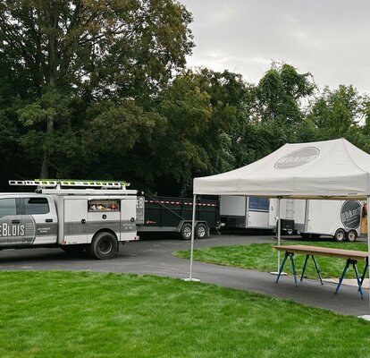 Tenda pieghevole DeBlois 4x2 stampata in bianco con pesi a terra in un giardino per l'artigianato