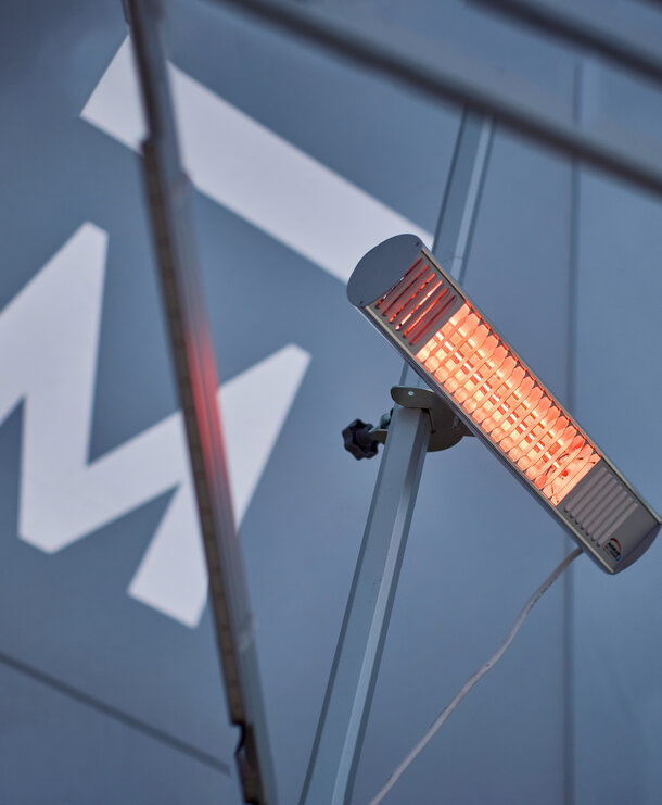 A mobile, infrared heater mounted on the interior mast of a Mastertent event tent.