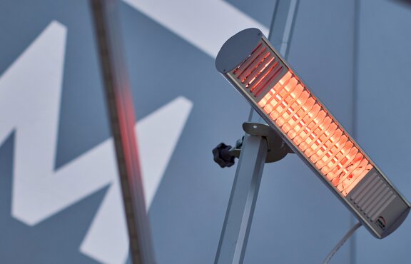 A mobile, infrared heater mounted on the interior mast of a Mastertent event tent.