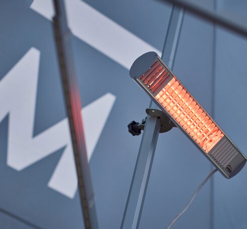 A mobile, infrared heater mounted on the interior mast of a Mastertent event tent.