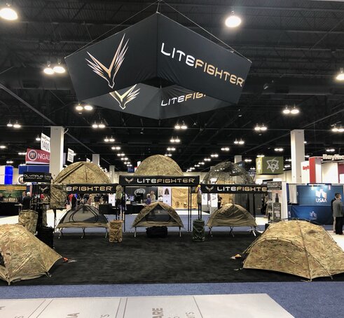 A retailer sells camping tents using a 10x10 custom canopy tent at a trade show. 