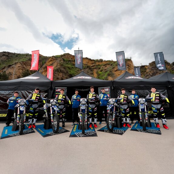 A cycling racing team posing for a picture in front of a row of Mastertent canopy tents.