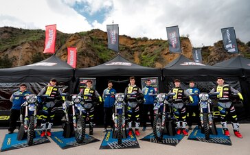 A cycling racing team posing for a picture in front of a row of Mastertent canopy tents.