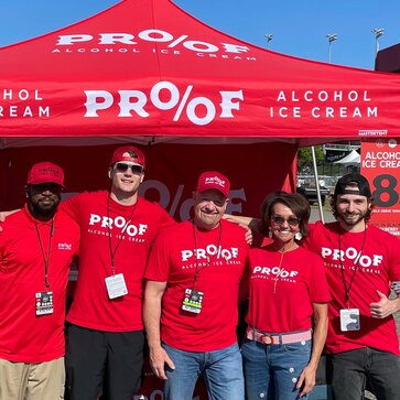 A company team in front of a printed red Mastertent Canopy tent.