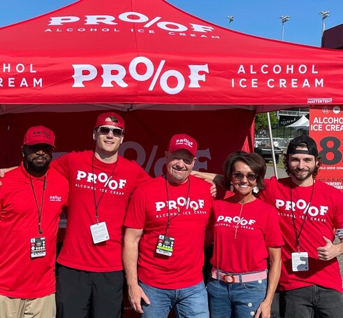 A company team in front of a printed red Mastertent Canopy tent.