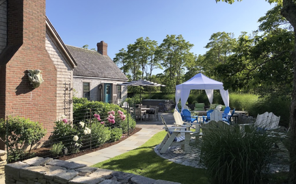 A white canopy tent with elegant corner curtains in a private backyard garden.
