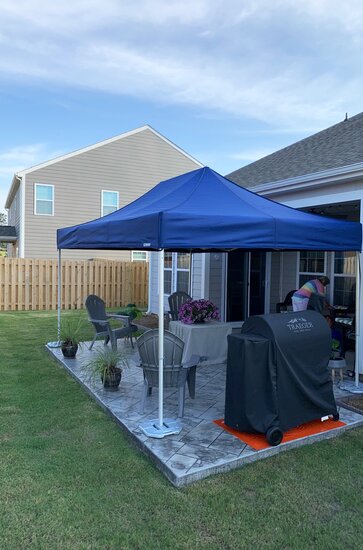 A blue Mastertent canopy tent set up in a residential backyard. 