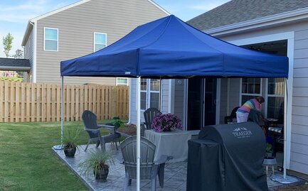 A blue Mastertent canopy tent set up in a residential backyard. 