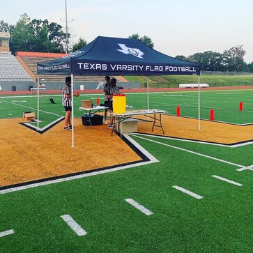 A 10x10ft Mastertent canopy tent set up on a football field for a flag football game.