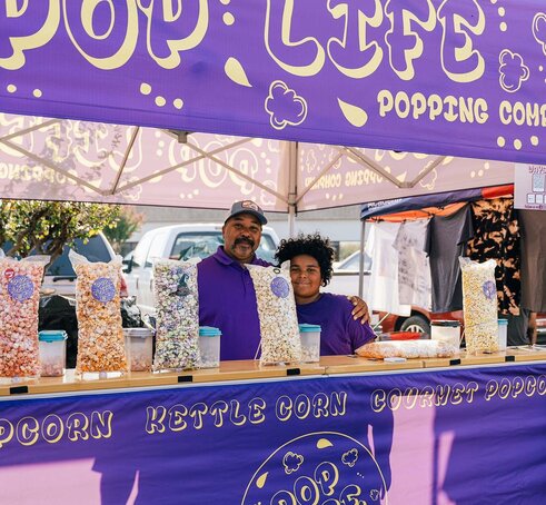 A purple 10x10ft printed canopy tent with counters to sell popcorn.