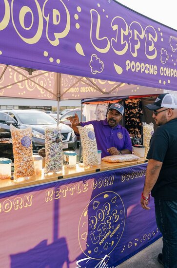 A purple 10x10ft printed canopy tent with counters to sell popcorn.