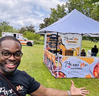 A man standing in front of his Mastertent printed vending canopy tent with awning on a grass field.