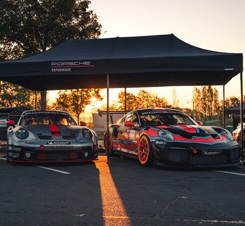 A black 20x10 canopy tent with custom printing and a black frame shades cars. 