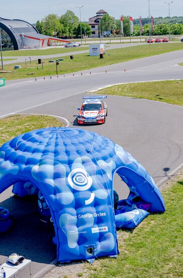 Large inflatable on a racetrack with car driving underneath. 