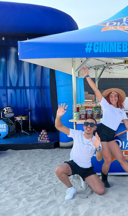Crowd pose for picture on the sand under Blue Diamond branded Mastertent square pavilion.