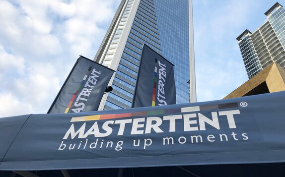 A close up view of Mastertent canopy tents and flags and Charlotte, NC skyscrapers.