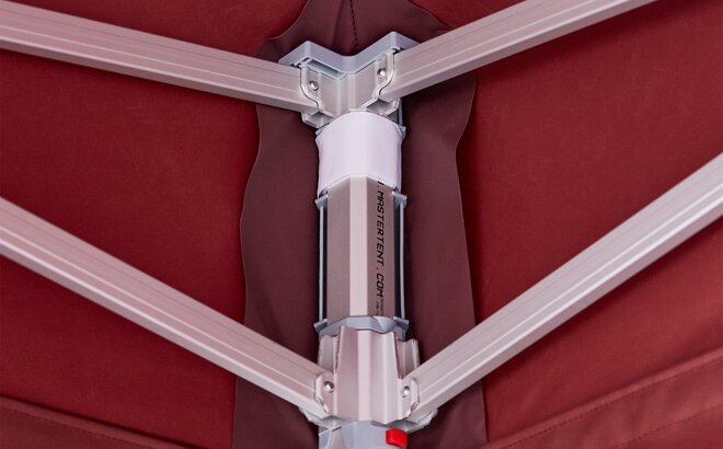 Inside view of an aluminum corner of a canopy tent frame with burgundy fabric wrapped around the top and outside