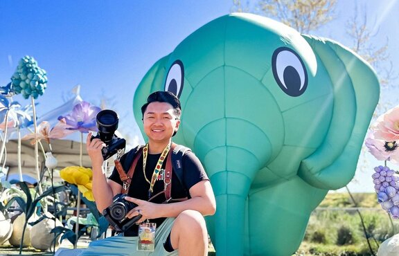 A photographer posing in front of a green custom inflatable elephant at Sabaidee Fest. | © @chueleephotodesign