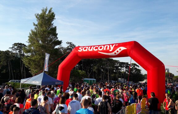 Crowd races under red Mastertent brand inflatable arch structure. 