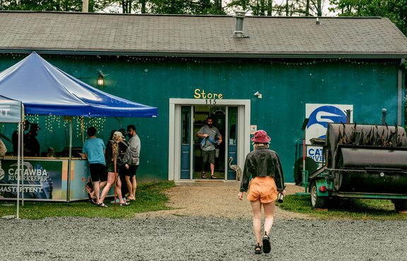 Crowd taking shelter from the rain under a Catawba Riverkeeper branded pavilion. 
