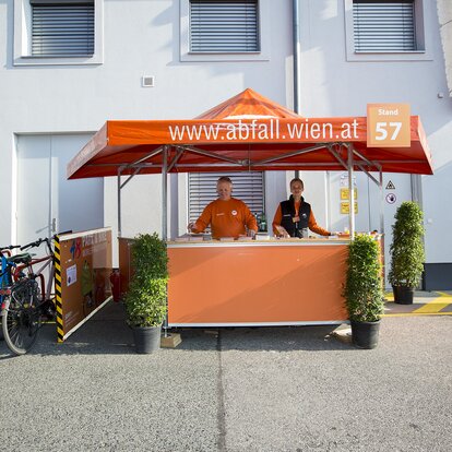Orange hexagonal pavilion with smiling attendants. 