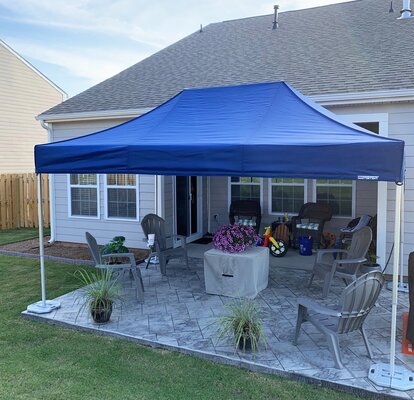 A blue Mastertent canopy tent set up in a residential backyard. 