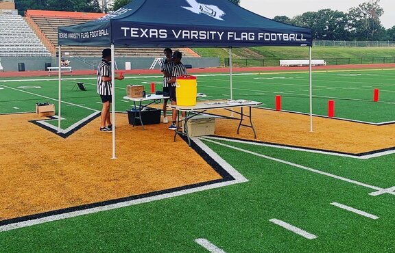 A 10x10ft Mastertent canopy tent set up on a football field for a flag football game.