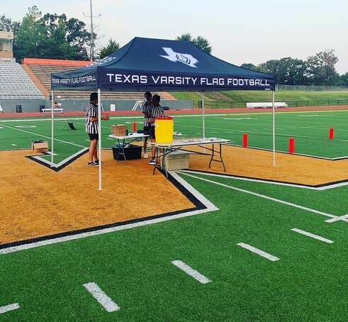 A 10x10ft Mastertent canopy tent set up on a football field for a flag football game.