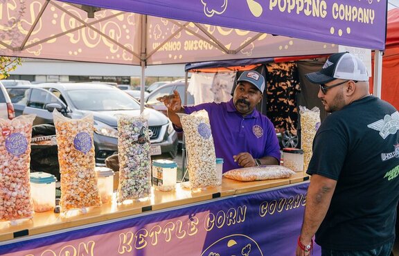A purple 10x10ft printed canopy tent with counters to sell popcorn.