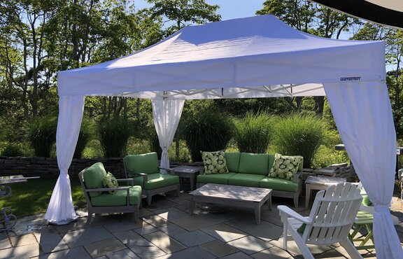 A 15x10 white canopy tent with a white frame creates shade above a backyard patio. 