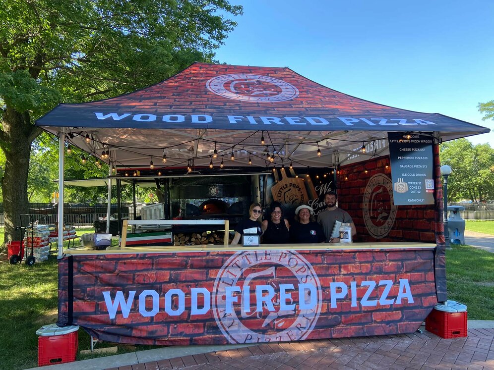 A custom 15x10 pizza tent with counters and sidewalls is used as a checkout counter and mobile food service. 