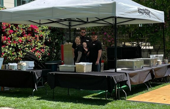 A 13x13 custom printed BBQ tent with a black tent frame and grey roof. 