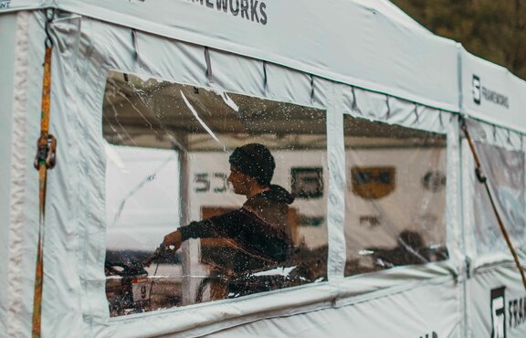 A 17x17 custom tent built for mountain biking with grey fabric, custom window fabrication, sidewalls and logo printing. 