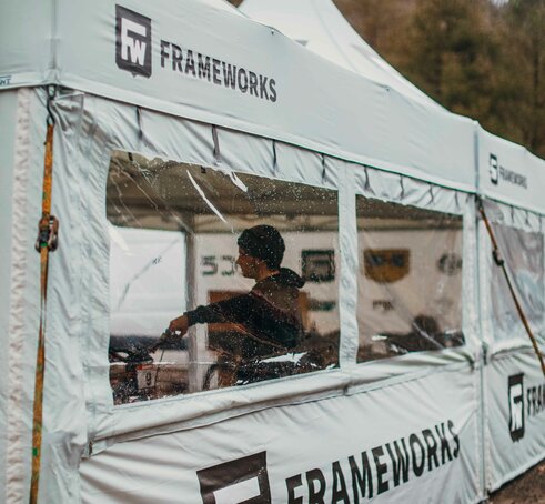 A 17x17 custom tent built for mountain biking with grey fabric, custom window fabrication, sidewalls and logo printing. 