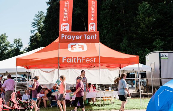Event and concert attendees sit underneath a custom orange 20x13 Mastertent canopy tent.
