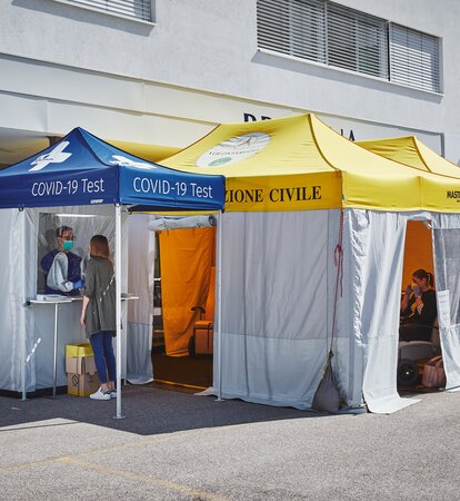 The test cabin for Covid-19 and for measuring fever is located in front of the Brixana Private Clinic. Next to it are two folding pavilions with yellow roofs.