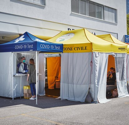 The test cabin for Covid-19 and for measuring fever is located in front of the Brixana Private Clinic. Next to it are two folding pavilions with yellow roofs.