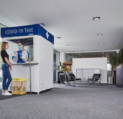 Fever is measured at the entrance to the company building for employees and customers. The employee carries out a check on the woman.