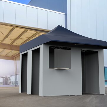 The vaccination tent is standing in front of a building. It has a blue roof and grey sidewalls.