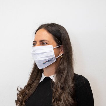 Eine Frau trägt eine weiße Baumwoll-Maske mit bunter Logo-Stickerei von Mastertent. 