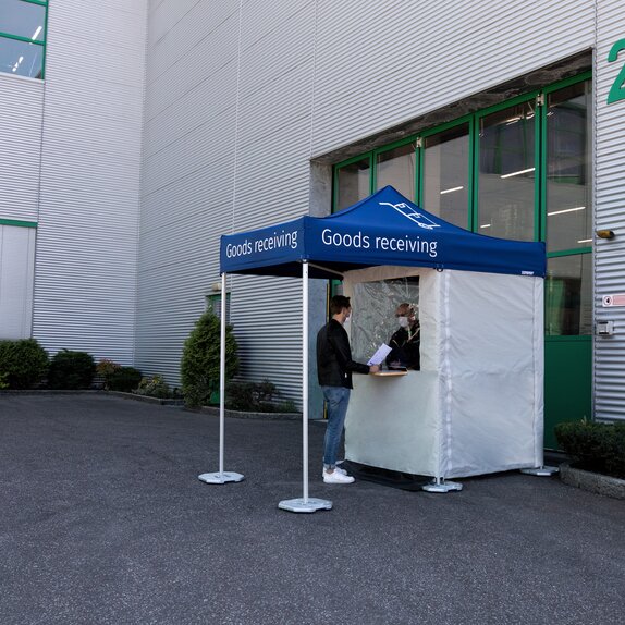 The man is standing in front of the goods receiving station. The employee is in the gazebo.