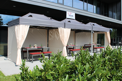 La terrazza di fronte al ristorante è coperta da tre gazebo pieghevoli. Sotto di loro ci sono delle tavole imbandite per gli ospiti.