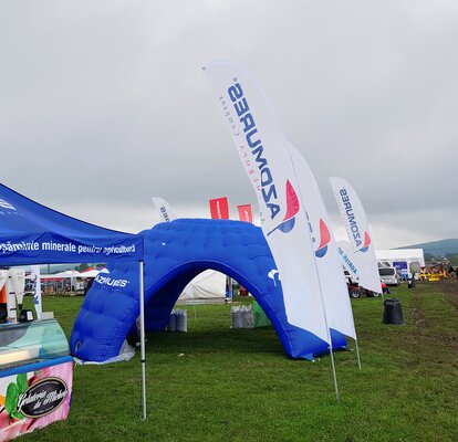 Blaues aufblasbares Eventzelt auf einer grünen Wiese bei einem Event. 