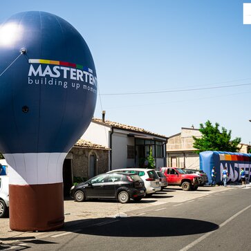 La imagen muestra dos grandes soportes publicitarios azules de Mastertent. Uno es alto y redondo, el otro es oblongo. Ambos llevan impreso el logotipo de Mastertent.