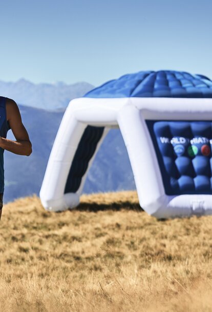 Marathonläufer rennt an einem blauen aufgeblasenen Werbeträger mit der Aufschrift "WORLD TRIATHLON" vorbei. 