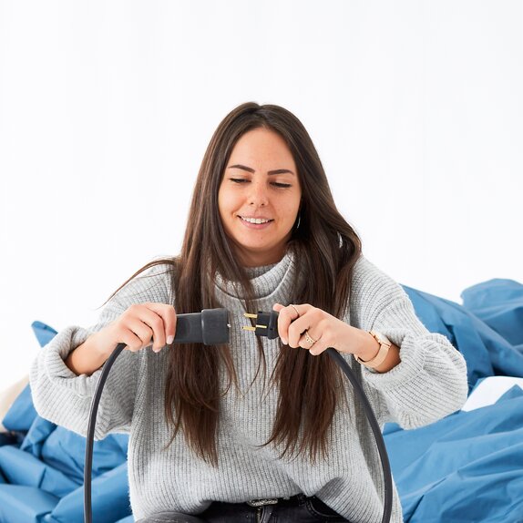 La donna sta inserendo la spina del ventilatore da 220 V per il gonmfiabile nella presa. 